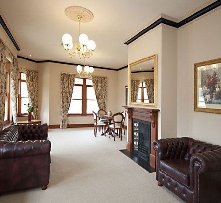 Framed-Art-Painting-In-A-Traditional-Apartment-Living-Room-Design-With-Fireplace-And-Brown-Chesterfield-Sofa-450x413